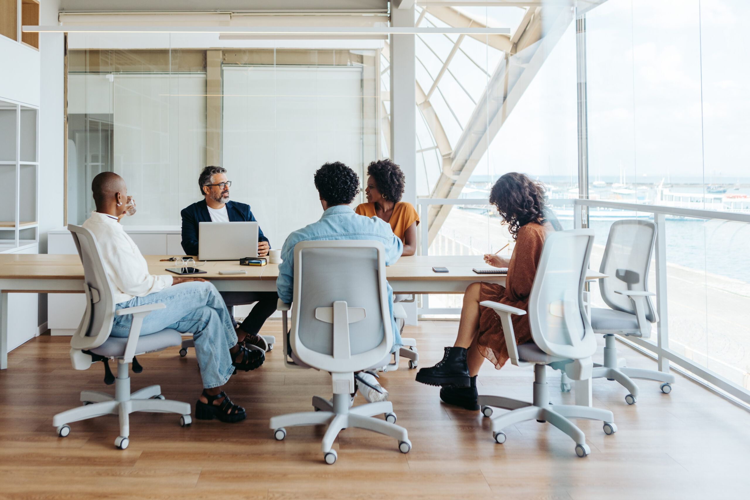 Business people collaborating in a modern office. They are engaged in a brainstorming session, discussing ideas and planning a project. The team demonstrates effective teamwork and emphasizes diversity and inclusion in the workplace.